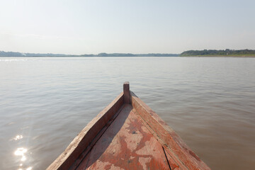 Point of view from the prow of a wooden boat traveling down the Amazon River