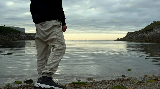 hombre lanzando una piedra al mar