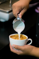 Close up of barista making latte art on a cup of hot milky latte