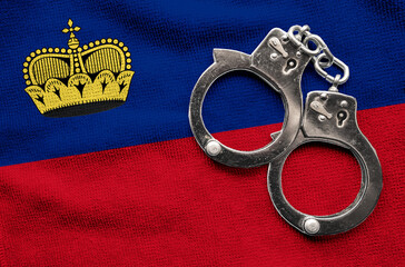 Flag of Liechtenstein and police handcuffs. Crime and offenses in country Concept
