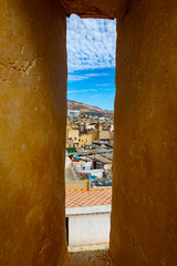 Cityscape viewed through a narrow tower opening.