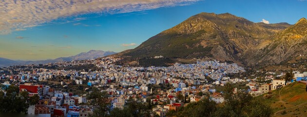 Hillside city, diverse buildings, cloudy sky.