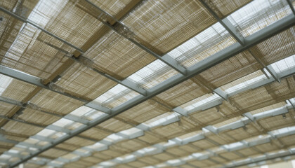 modern architectural ceiling design features grid of woven bamboo panels, creating natural and textured aesthetic. structure is supported by metal beams, offering blend of organic and industrial