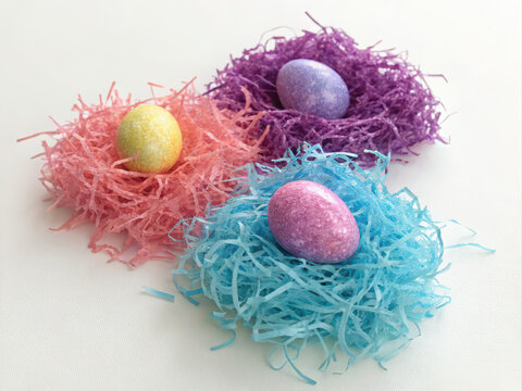 Pastel Easter eggs nestled in colorful shredded paper nests