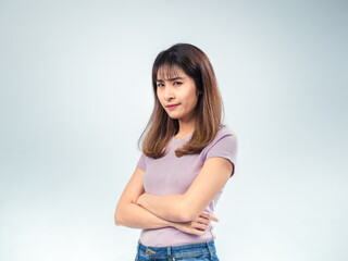 Asian woman in a purple t-shirt standing with crossed arms and a skeptical facial expression, looking directly at the camera against a clean light background