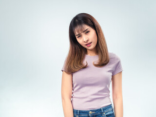 Obraz premium Asian woman in a purple t-shirt looking down with eyes closed, showing a tired or disappointed expression against a plain studio background