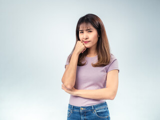 Asian woman in purple t-shirt and jeans looking to the side with thoughtful expression, hand...