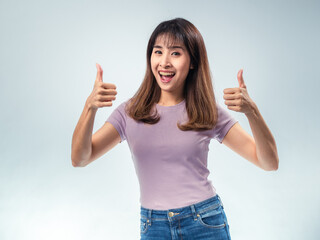 Asian woman in a purple t-shirt and jeans smiling confidently, winking, and showing a thumbs-up...