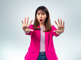 Asian woman in pink blazer and purple t-shirt holding both hands forward in a stop gesture with...