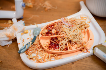 Messy table with spilled noodles and sauce in a casual dining environment after a meal with children