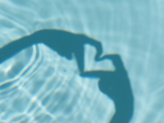 Selective focus. Hands creating a heart shape shadow in swimming pool.