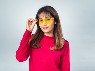 Asian woman in red sweater posing with yellow sunglasses, slightly smiling with confident and...