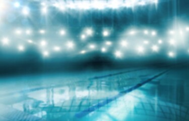 Featuring empty tiled pool with floating lane dividers, reflecting stadium lights and shining water