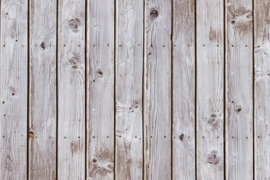 Vertical weathered planks are forming full-frame flat design showing grain and nail holes