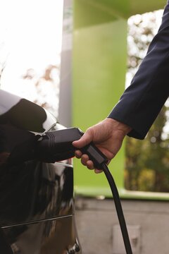 Fototapeta Man charging electric car at charging station