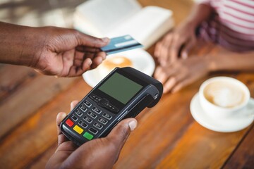 Man paying with NFC technology on credit card in cafe