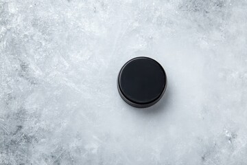 A black, circular container rests on a textured, icy-grey surface.  The container is glossy and appears smooth