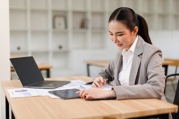 Asian professional analyst business woman sitting at office desk working on laptop thinking on...