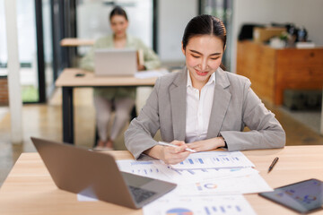 Asian professional analyst business woman sitting at office desk working on laptop thinking on project plan, analyzing marketing or financial data online, watching elearning webinar.