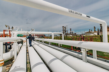 Male worker inspection at steel long pipes and pipe elbow in station oil factory during refinery...