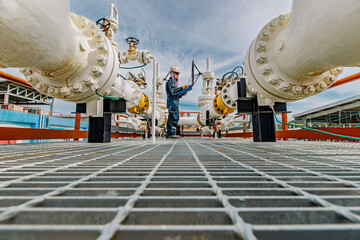 Male worker inspection at steel long pipes and pipe elbow in station oil factory during refinery...