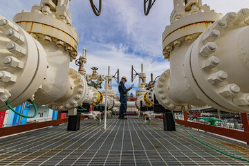 Male worker inspection at steel long pipes and pipe elbow in station oil factory during refinery...