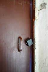 brown old iron door to house with black padlock