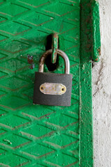 there is an old iron lock hanging on the closed green iron door
