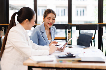 Portrait of Two casual asian business women at work.doing planning analyzing the financial report,...