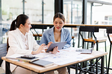 Portrait of Two casual asian business women at work.doing planning analyzing the financial report,...