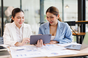Portrait of Two casual asian business women at work.doing planning analyzing the financial report,...