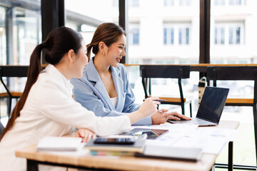 Portrait of Two casual asian business women at work.doing planning analyzing the financial report,...