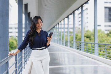 Businesswoman using smartphone on modern walkway in city center