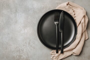 Matte black plate, fork, knife atop beige linen napkin on grey textured surface