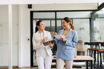 Two Young Asian Happy business women standing and holding tablet in hand confidence leadership in a...