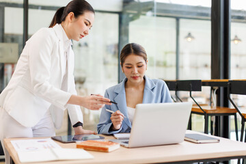 Two Young Asian Happy business women discuss new startup project Idea presentation, analyze planning and financial statistics and investment market at office.
