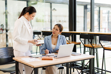 Two Young Asian Happy business women discuss new startup project Idea presentation, analyze planning and financial statistics and investment market at office.
