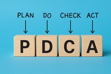 Pdca wooden blocks illustrating plan, do, check, act cycle