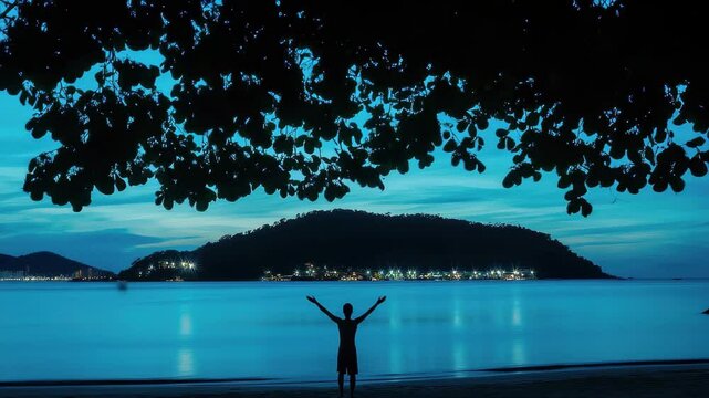 Silhouette of a man overlooking Man Island at night from Nai Harn Beach, Night silhouette of Man island seen from Nai Harn beach Phuket, Thailand