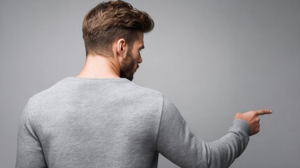 A man in a gray sweater pointing at something