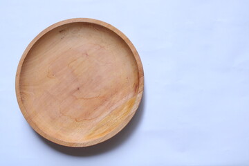 Top view of an empty round wooden plate on a white background