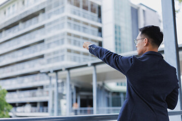 Businessman pointing towards modern building in urban setting © Phimwilai