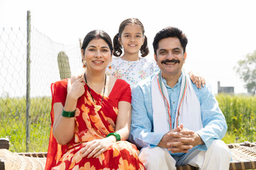 Happy rural family sitting on traditional bed at village