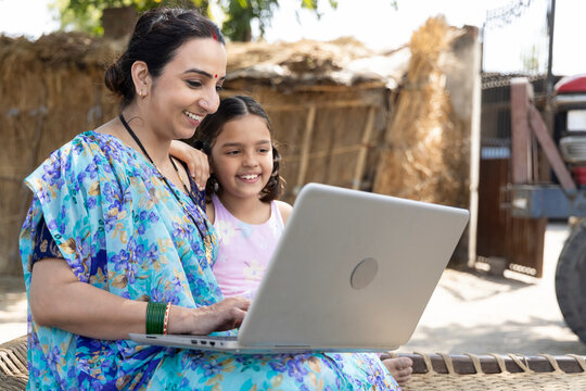 Happy mother with her daughter using laptop at village.