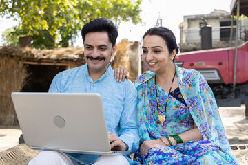 Villagers using laptop sitting with the banker or insurance agent outside the home