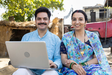 Villagers using laptop sitting with the banker or insurance agent outside the home