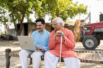 Father and son using laptop at village.
