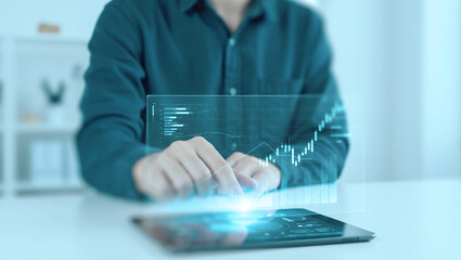 Business professional uses a finger to tap and interact with a holographic chart projected from a tablet.