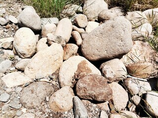 Natural river rocks, river boulder stone, or round river stones that are on the surface of grassy...