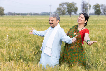 Husband and wife harvesting crops in farm 